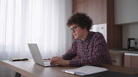 A-curly-man-with-glasses-at-his-desk-shows-a-picture-with-graphs-in-a-laptop-camera